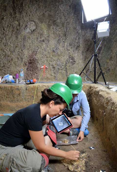 Arqueólogos registrando los huesos hallados en el interior de la cámara funeraria. (Ministerio de Cultura griego)