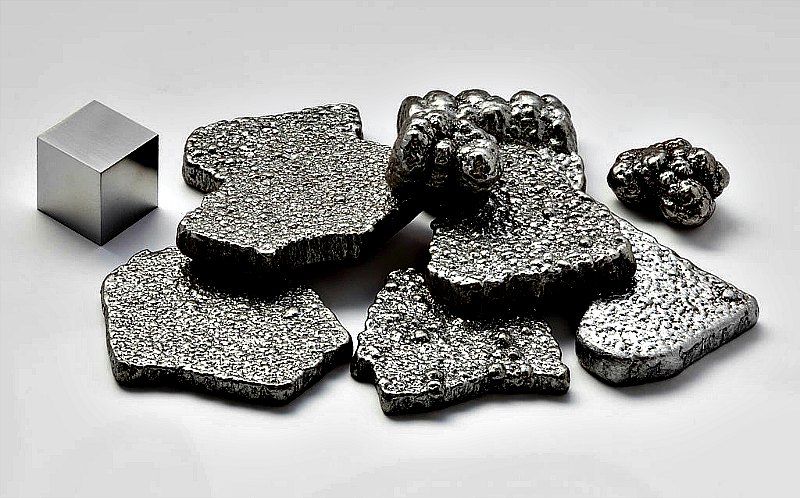 Fragmentos de hierro puro (99.97 %+), refinado electrolíticamente, junto a un cubo de 1 cm3 de hierro de alta pureza (99.9999 %). (Public Domain)