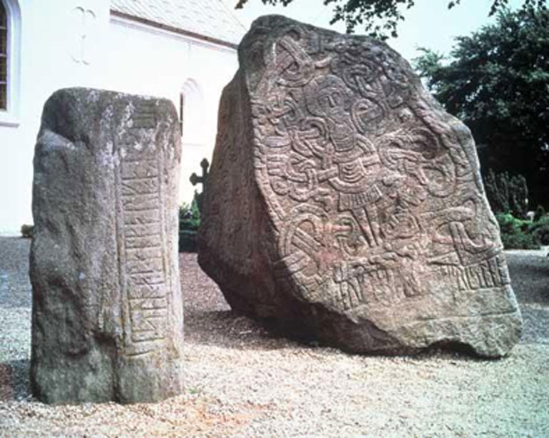 La piedra rúnica de Harald con la imagen de Cristo se alza ante la Iglesia de Jelling. Junto a ella se encuentra la piedra de su padre Gorm creada para la reina Thyra, madre de Harald. (Nationalmuseet - The National Museum of Denmark)