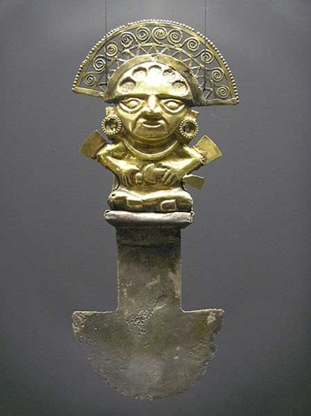 Tumi hallado en Sipán, Perú (850 d. C. – 1050 d. C.) La figura de oro que decora el mango representa a un dignatario ricamente ataviado, posiblemente un sacerdote, quien a su vez también empuña en su mano izquierda un tumi sacrificial. En los lóbulos de las orejas de esta figura había originalmente turquesas incrustadas. El reverso de este tumi está decorado con una lámina de oro en forma de lágrima. (Public Domain)