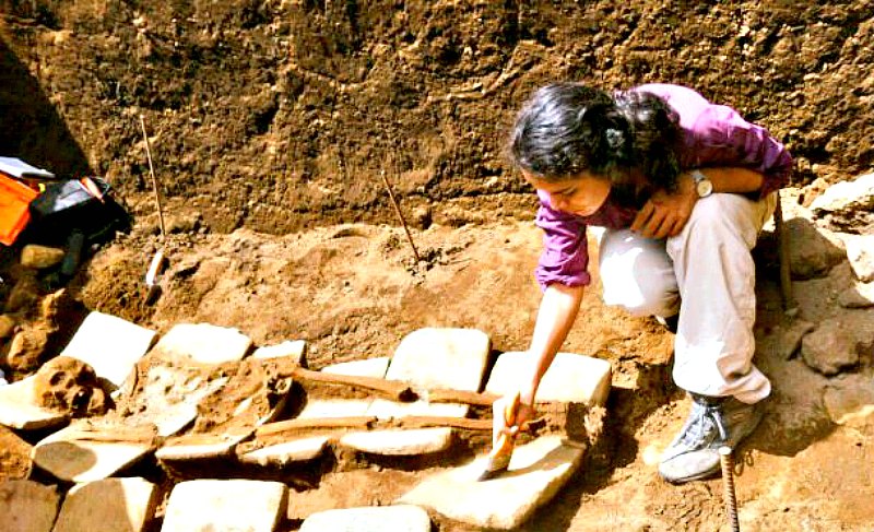Arqueóloga trabajando sobre algunos de los restos óseos hallados recientemente en Nicaragua. En esta fotografía se aprecia claramente uno de los lechos de metates sobre los que fueron depositados algunos de los cadáveres. (Fotografía: Canal 4)