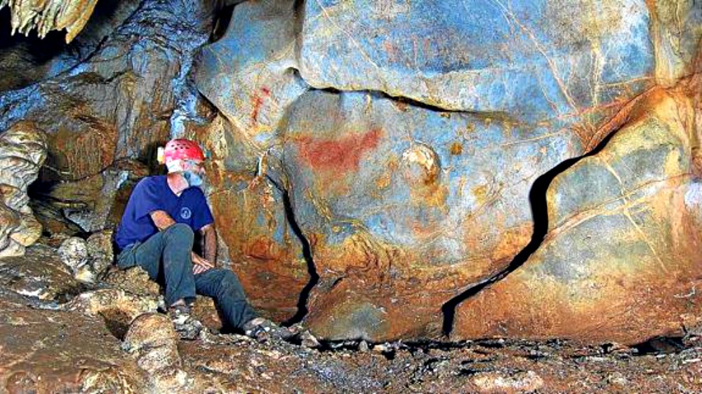 Portada - Un espeleólogo del grupo ADES observa el caballo rojo, una pintura rupestre recientemente descubierta cuya datación definitiva aún no se ha realizado. (Fotografía: El Correo/ADES)
