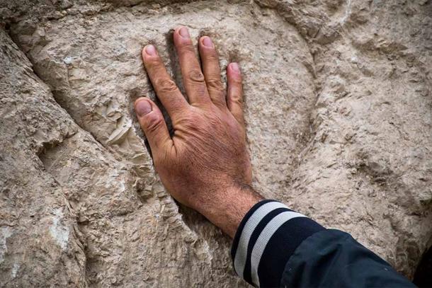 Mano moderna probando el tamaño de la huella de la mano misteriosa. (Yuli Schwartz / Autoridad de Antigüedades de Israel)